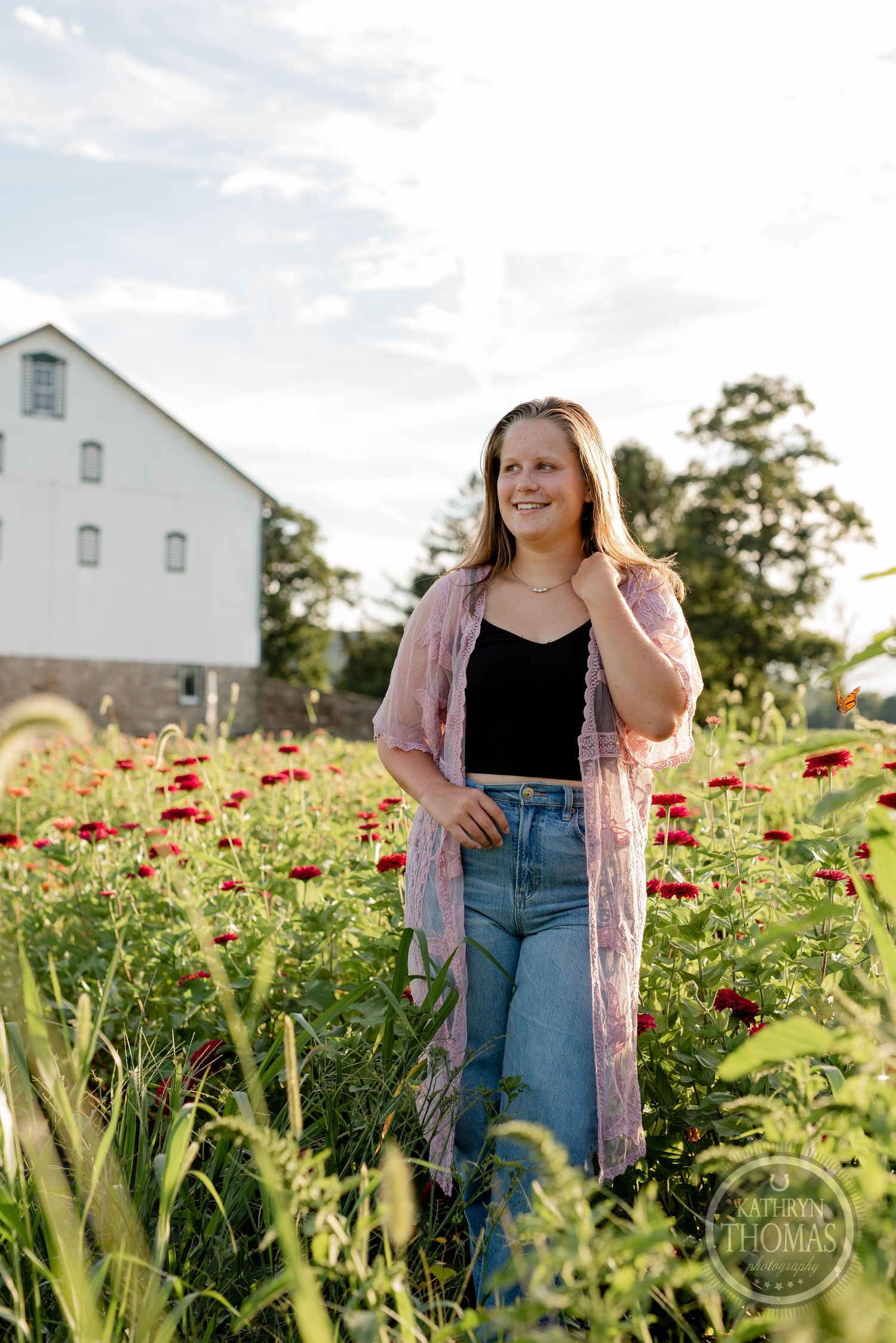 A sunny portrait in a field of red poppies and wildflowers with a white barn backdrop.