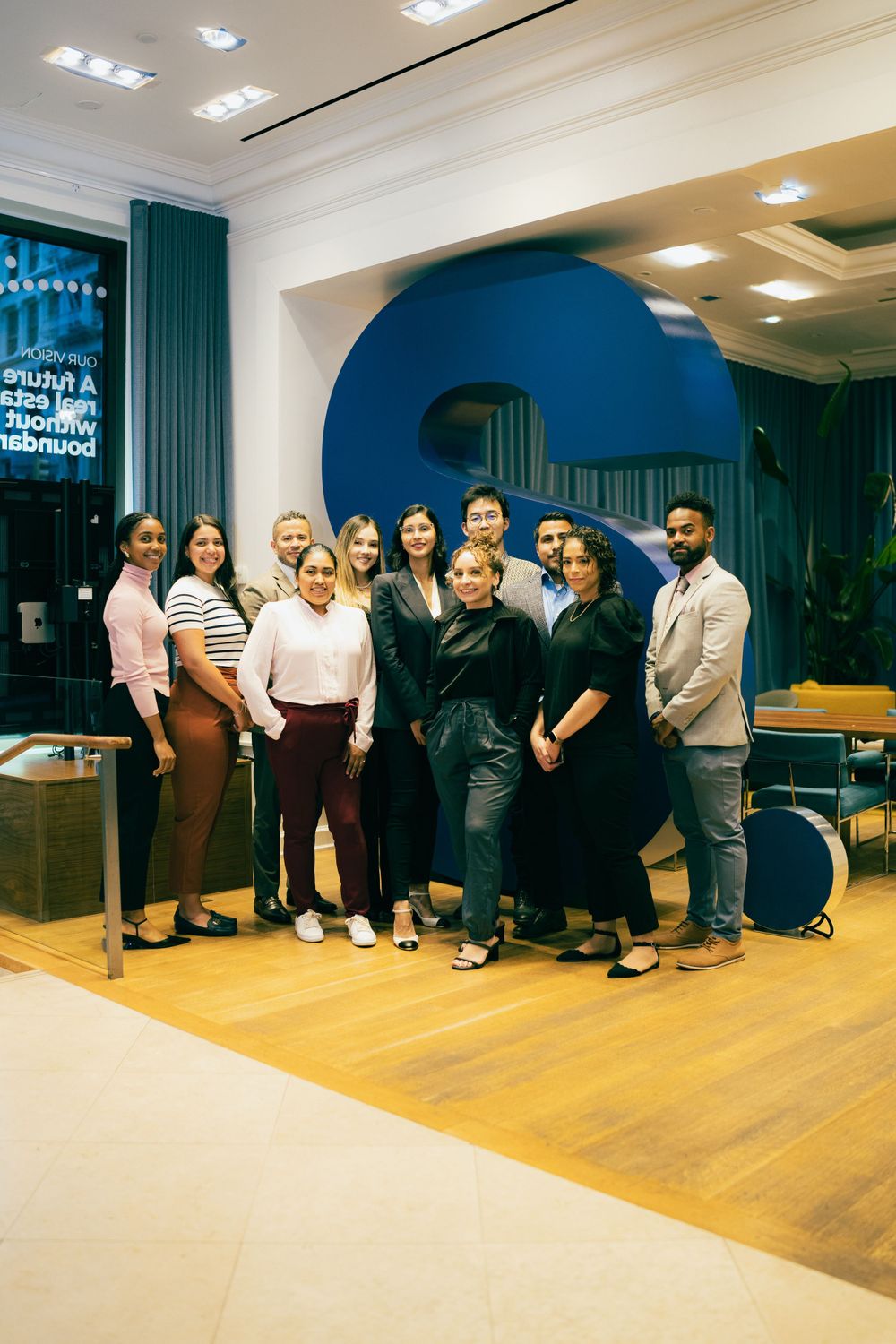 Team members posing together on wooden flooring in a modern office space.