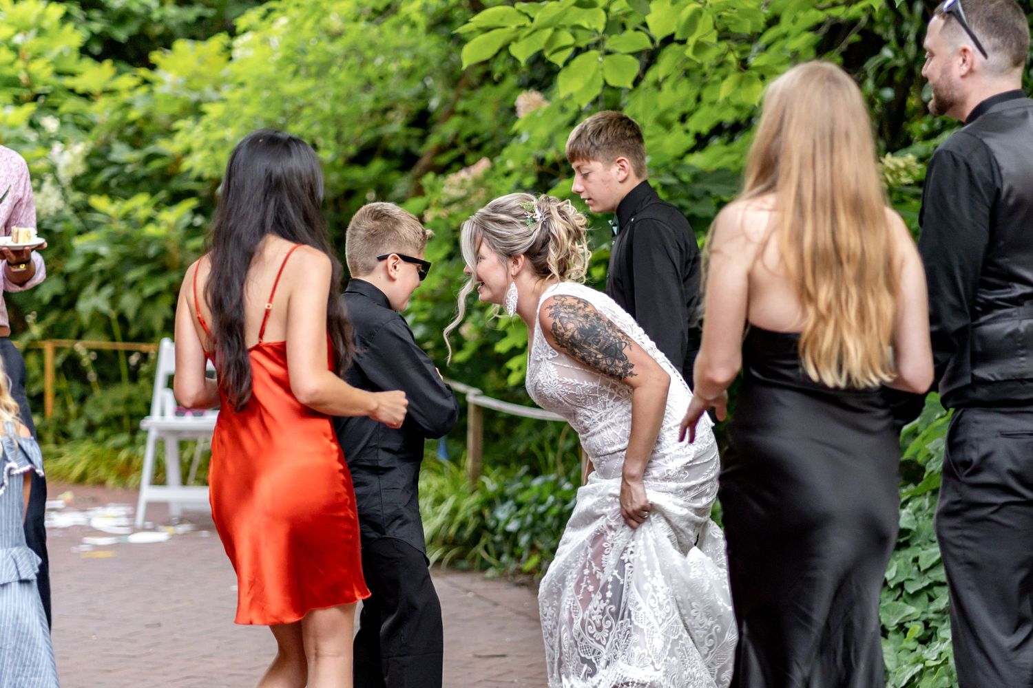 Wedding guests enjoying a casual outdoor dance party on a patio under greenery.