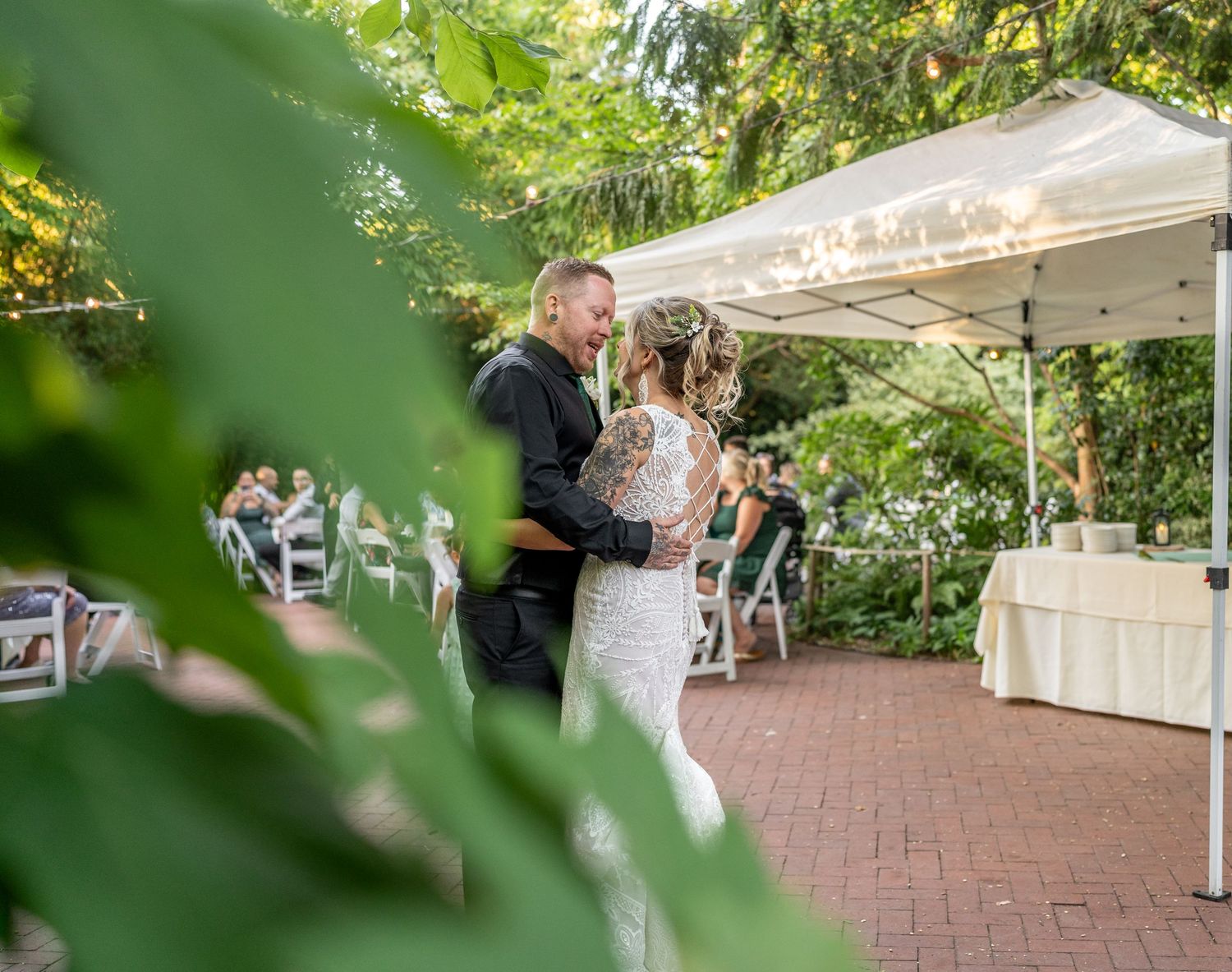 Couple sharing a dance moment under a white tent at an outdoor reception.