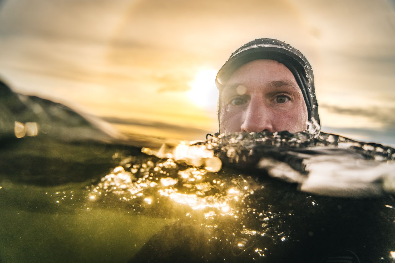 Split-shot photo of a swimmer in water during golden hour sunset.