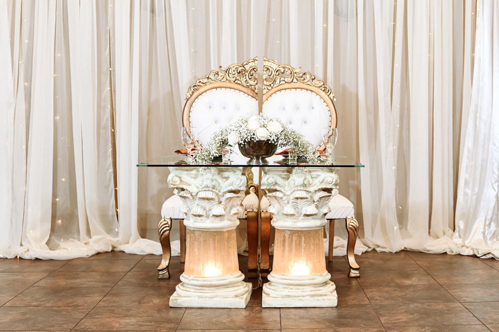 Elegant vintage-style sweetheart table setup with ornate gold mirror and white draping.