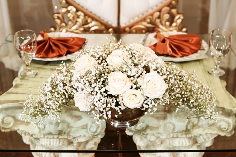 Wedding table decoration featuring white roses and baby's breath centerpiece with coral napkins.