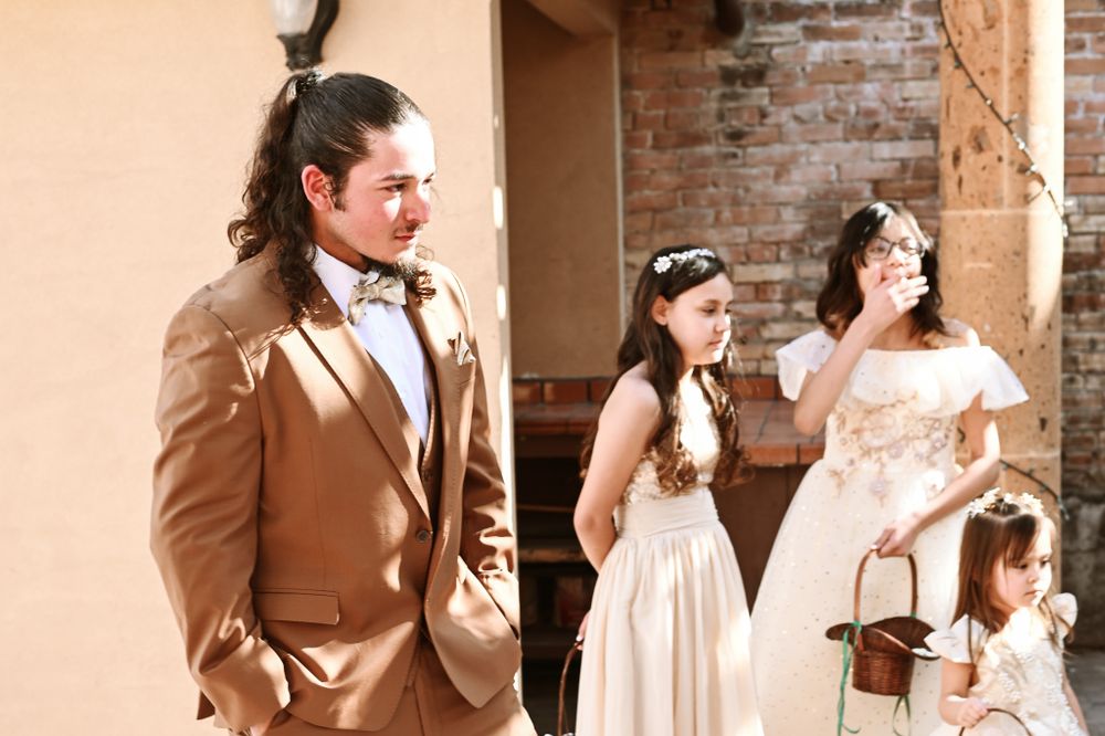 Wedding party members gathered outside a rustic venue with brick walls and stucco finish.