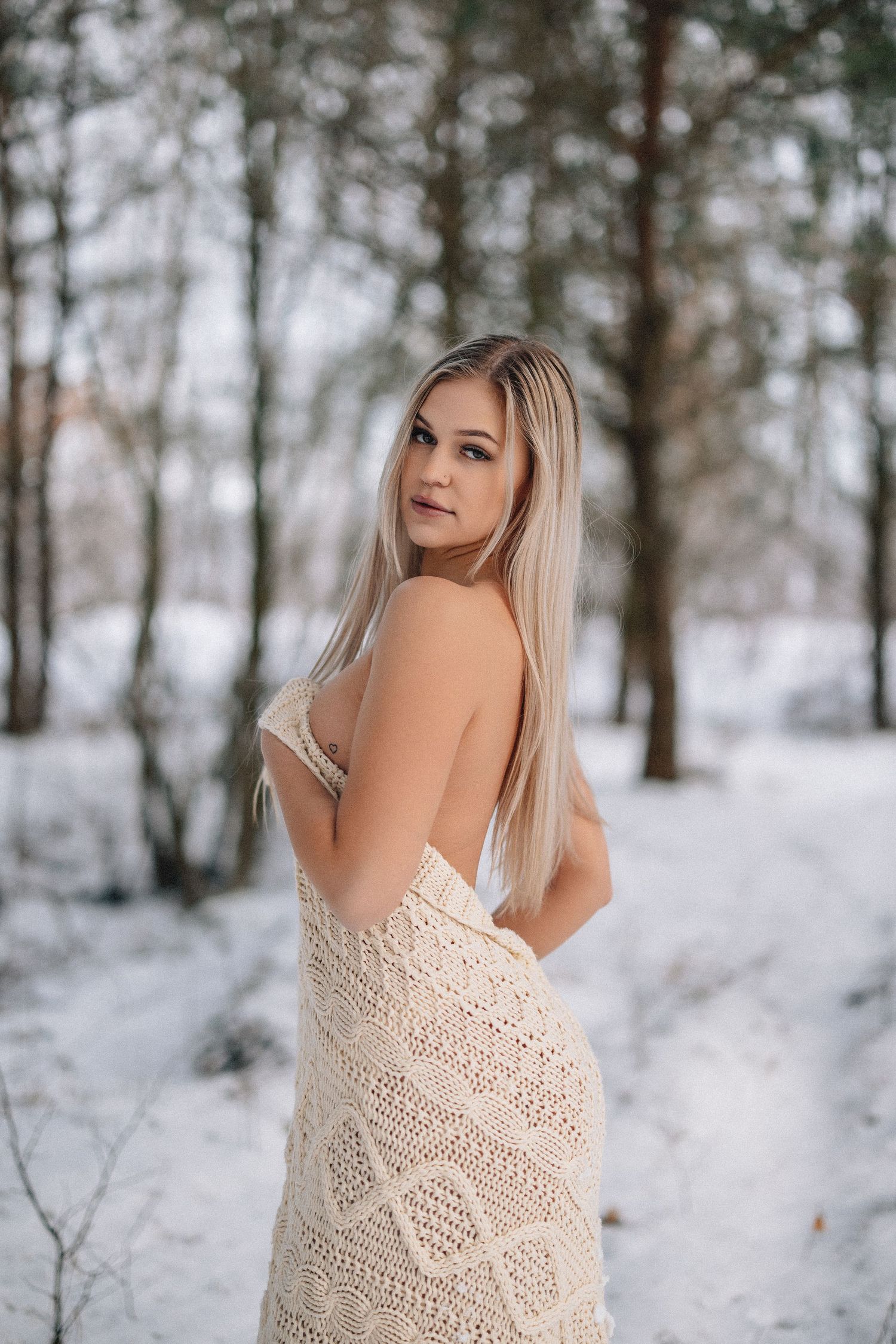 Elegant outdoor portrait against snowy forest backdrop with cream lace wrap.
