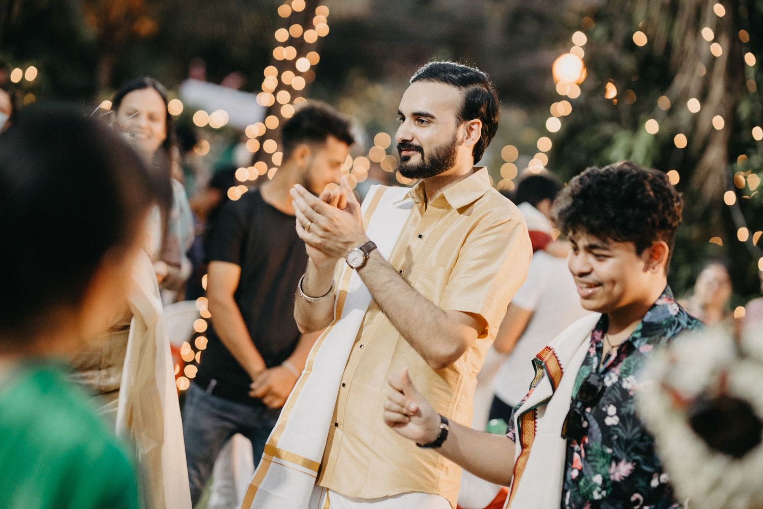 Evening celebration with guests dancing under string lights at an outdoor event.