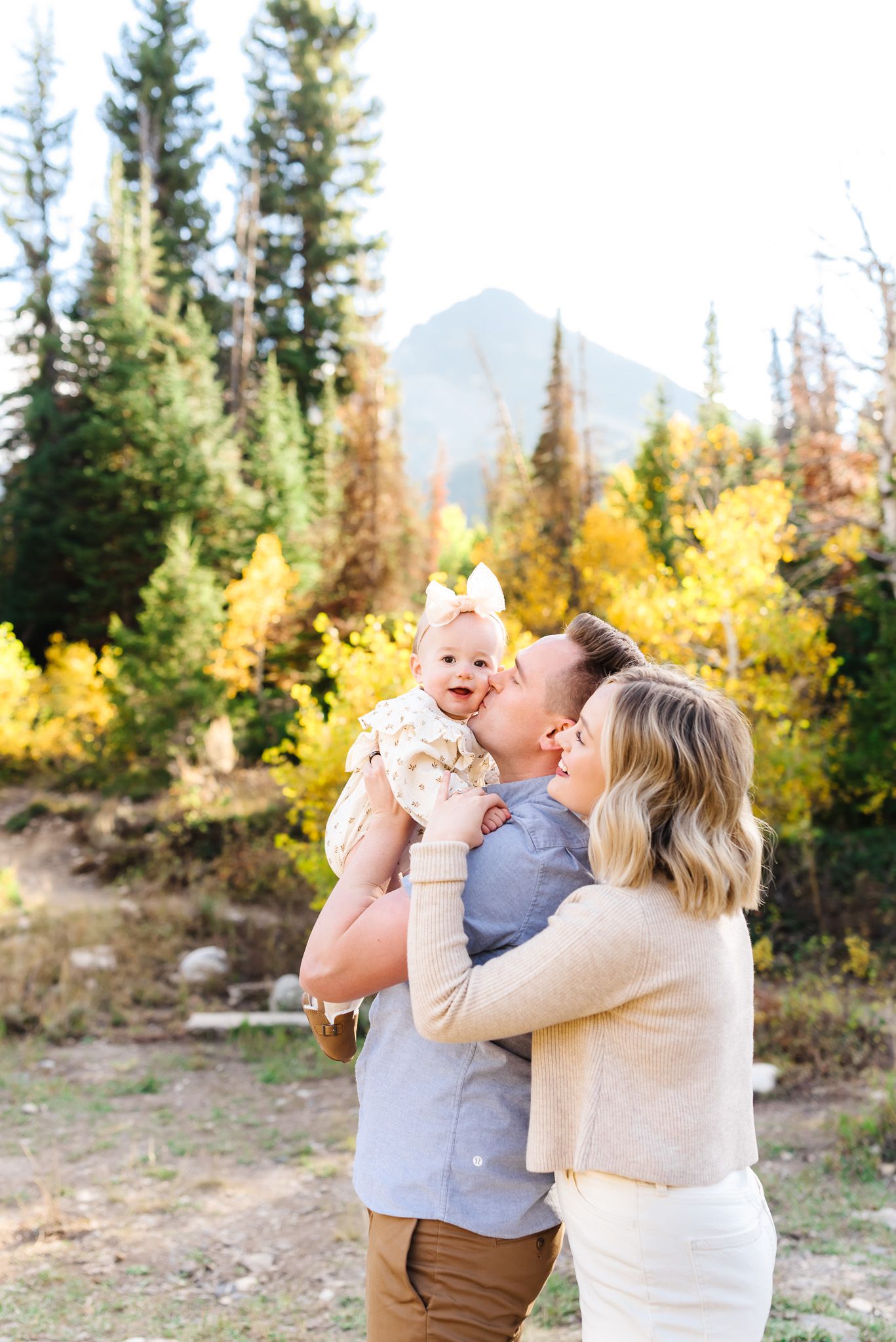 Family sharing joyful moments against backdrop of golden aspens and mountain scenery.