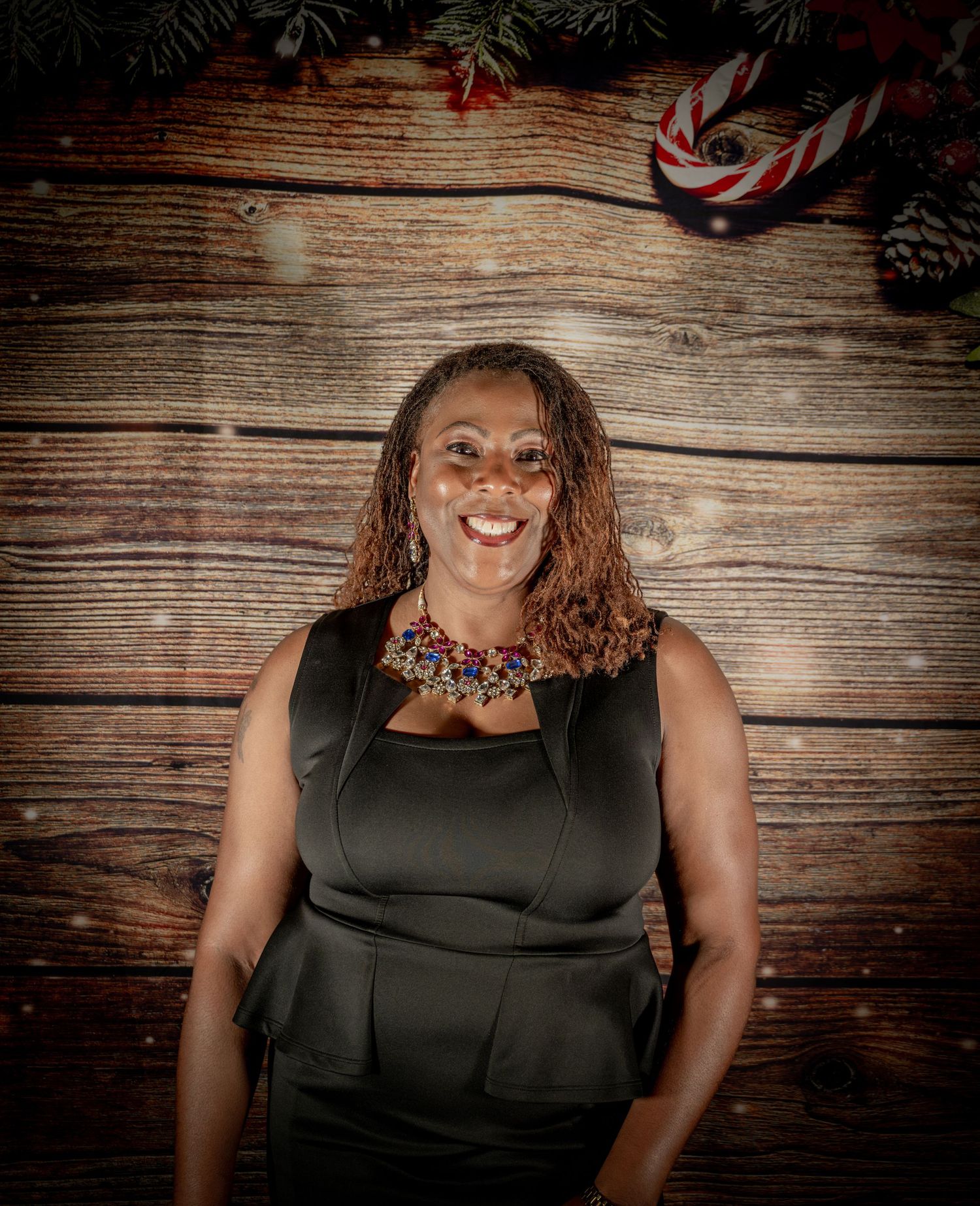 Person in black formal dress poses against rustic wooden wall background.