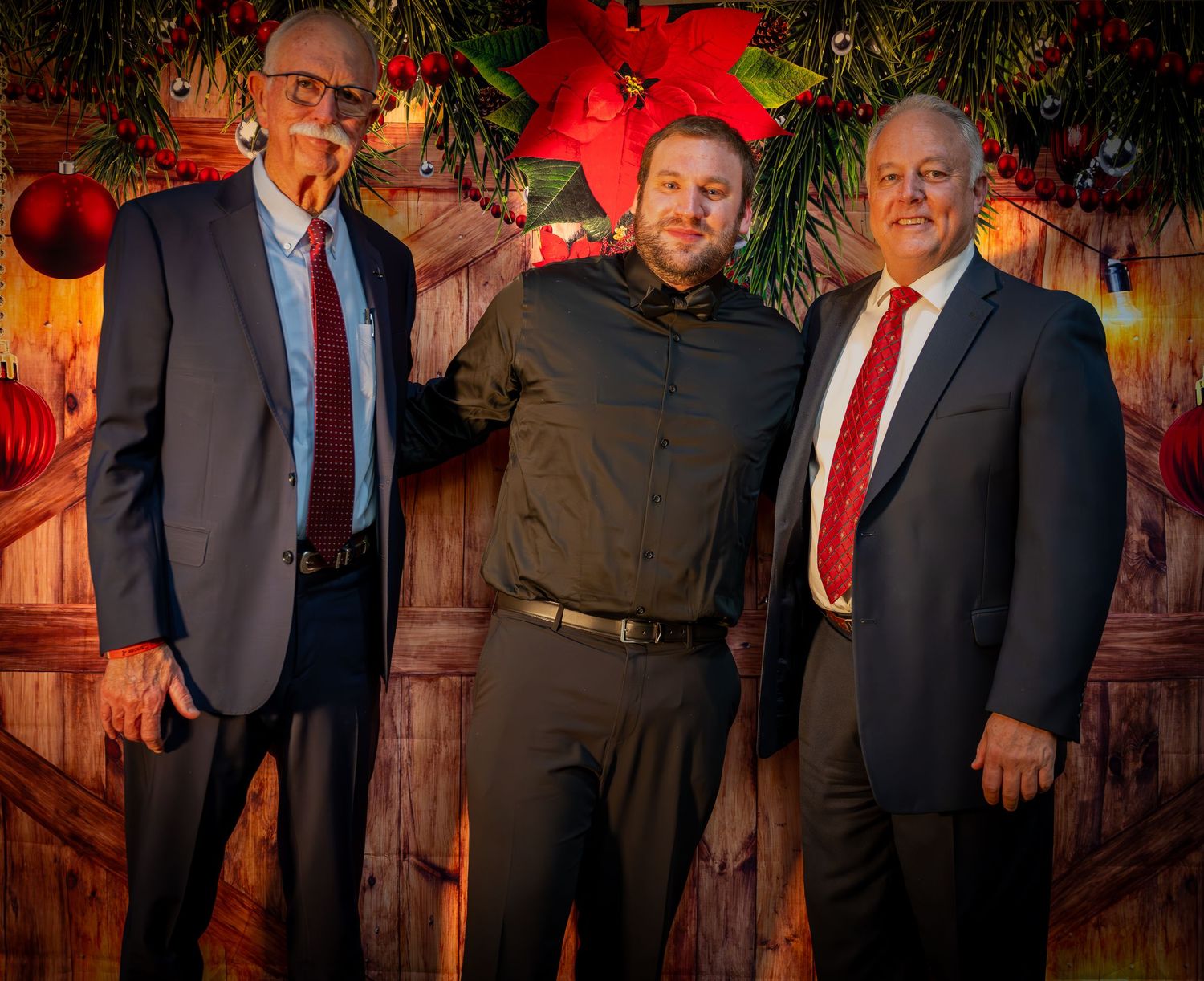 Professional gathering captured in warm lighting with holiday greenery and red decorative elements.