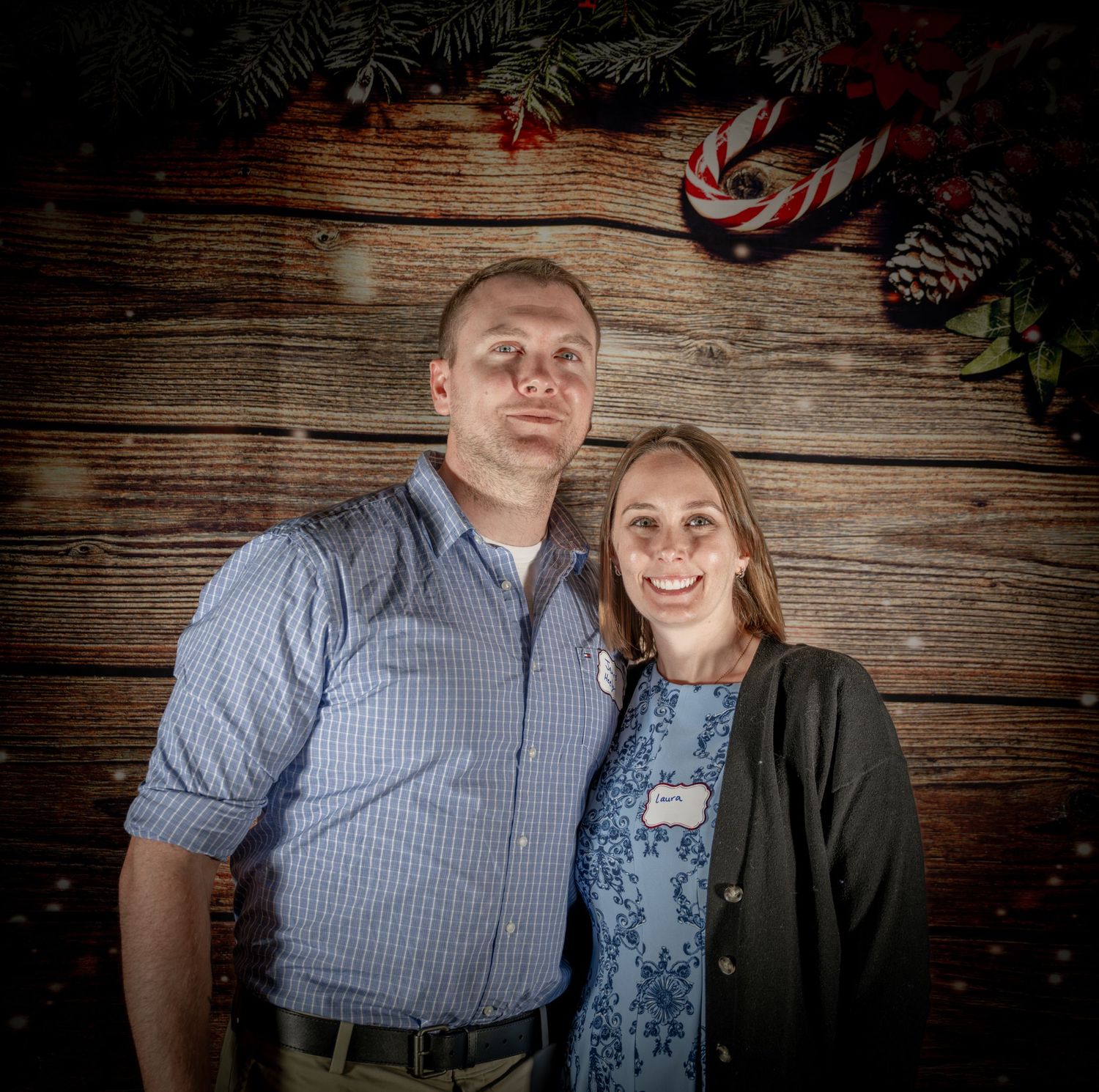 Casual couples photo session against rustic wooden wall with ambient lighting.