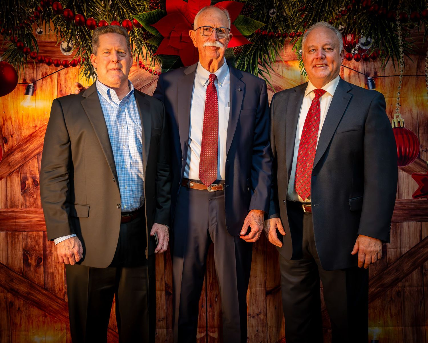 Business professionals gathered at a formal event with holiday decorations in warm lighting.