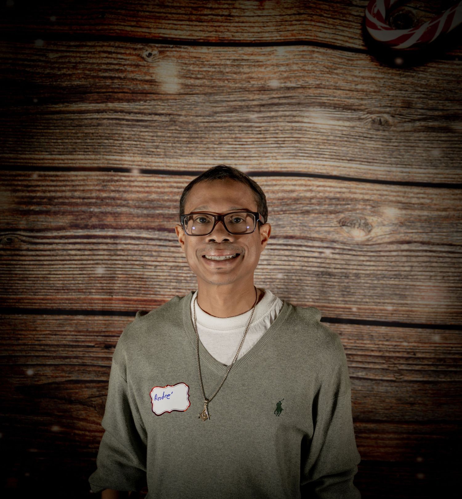 Portrait against rustic wood wall featuring casual winter attire and glasses.