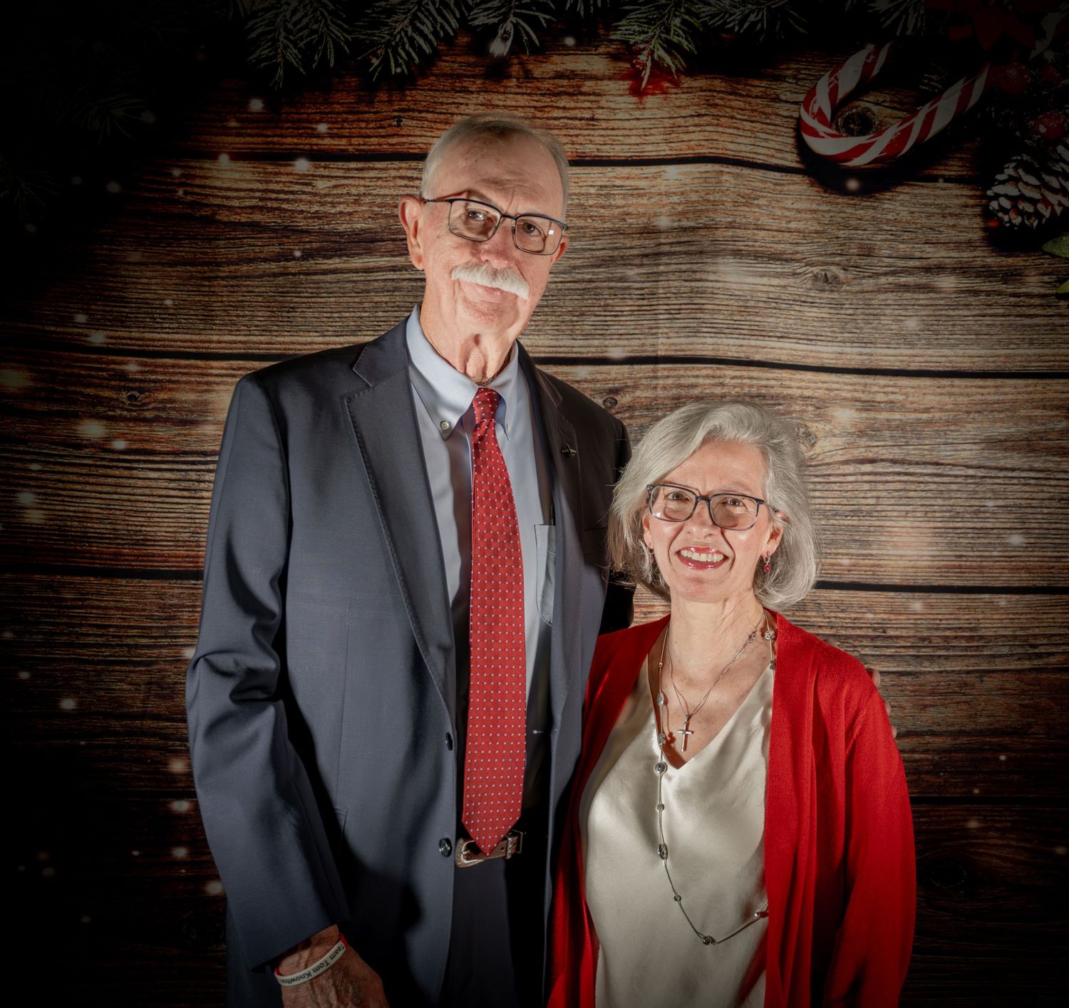 Formal holiday portraits with couples against rustic wood paneling.