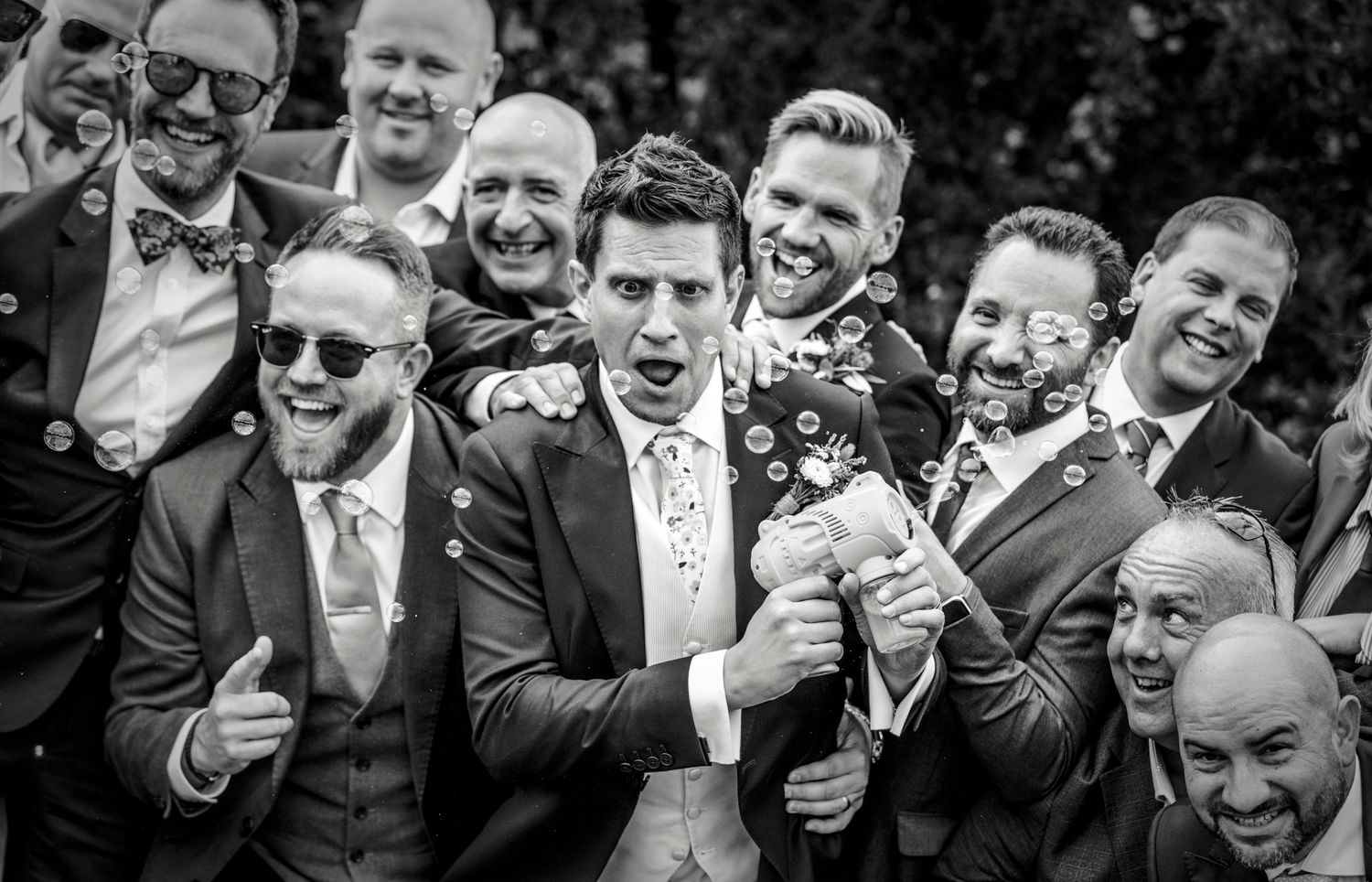 Black and white candid photo of wedding guests laughing and celebrating.
