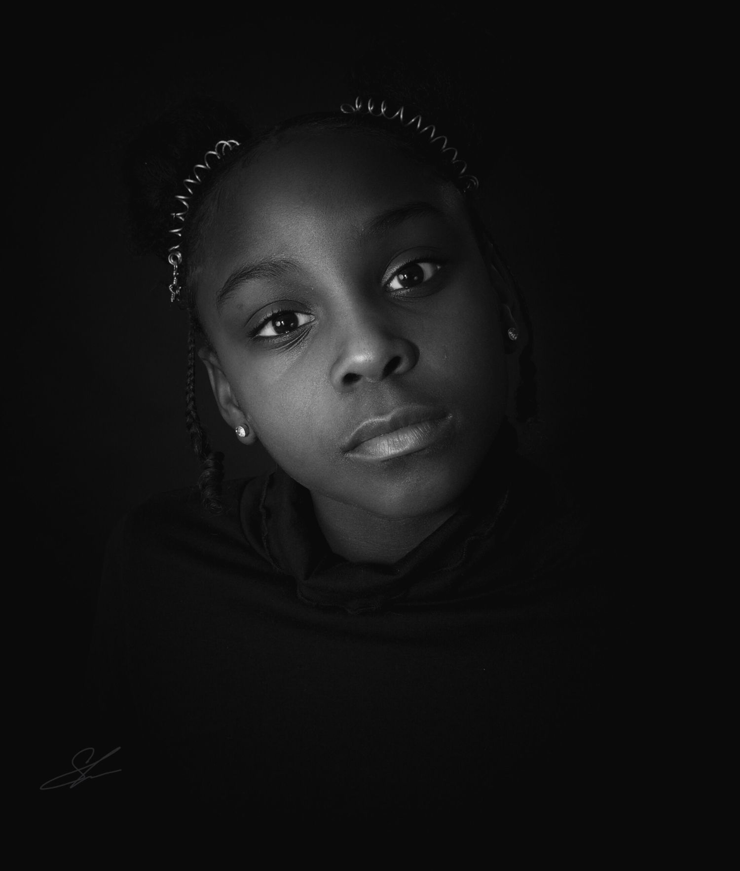Artistic black and white portrait showing braided hairstyle against dark background.