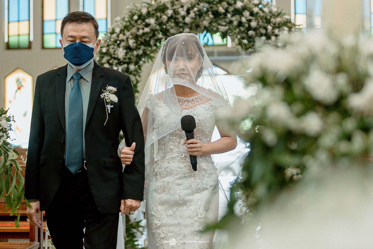 Church wedding ceremony with floral arch decorations and white veil.