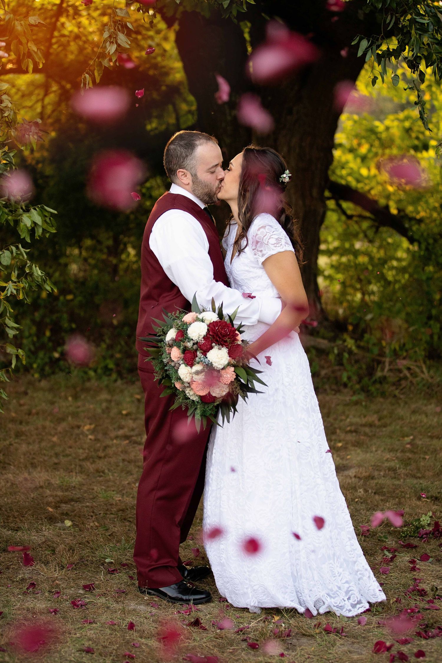 bride and groom kiss with flower petals scattered green house two rivers
