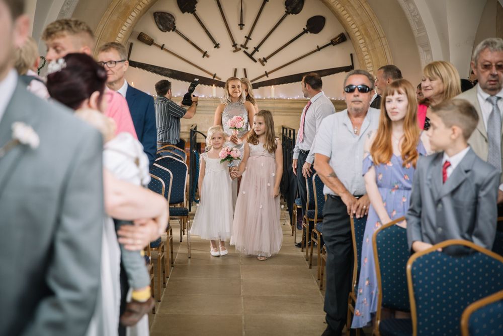 Wedding ceremony in an ornate room with arched ceilings and guests seated in rows.