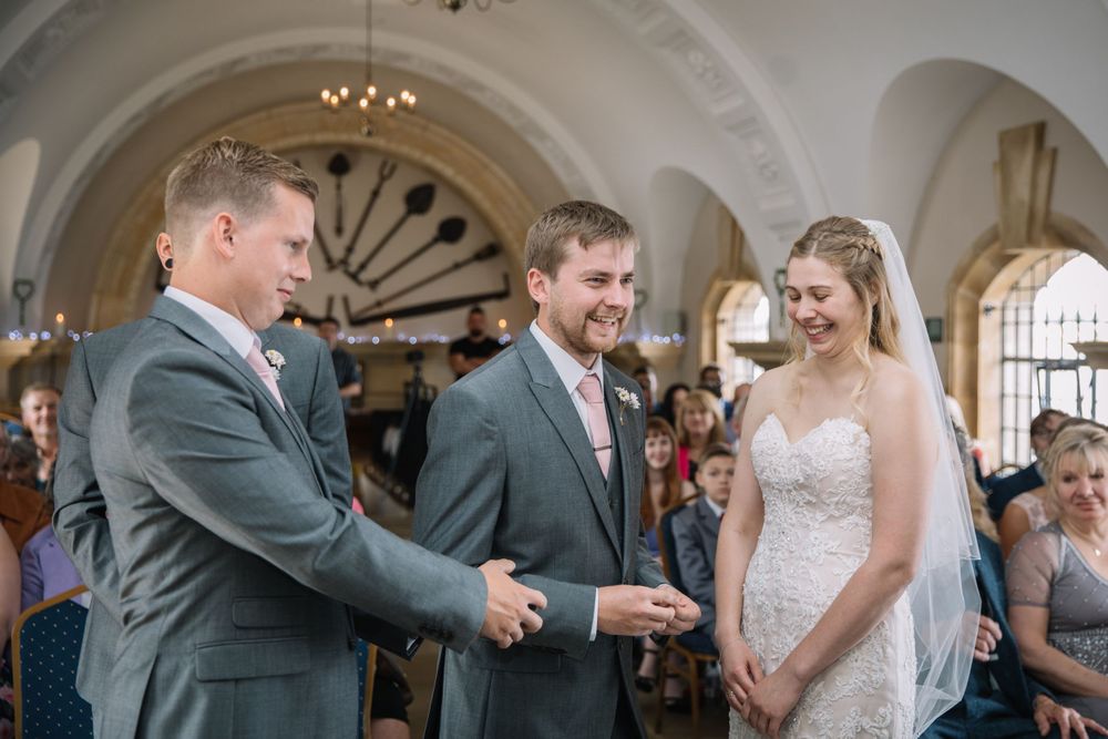 A candid moment between wedding party members in an ornate venue with arched ceilings.