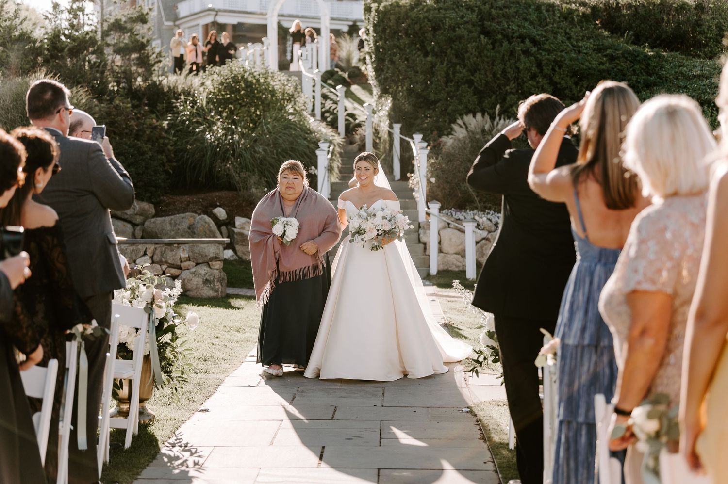 A beautiful outdoor wedding ceremony with white chairs and floral decorations.