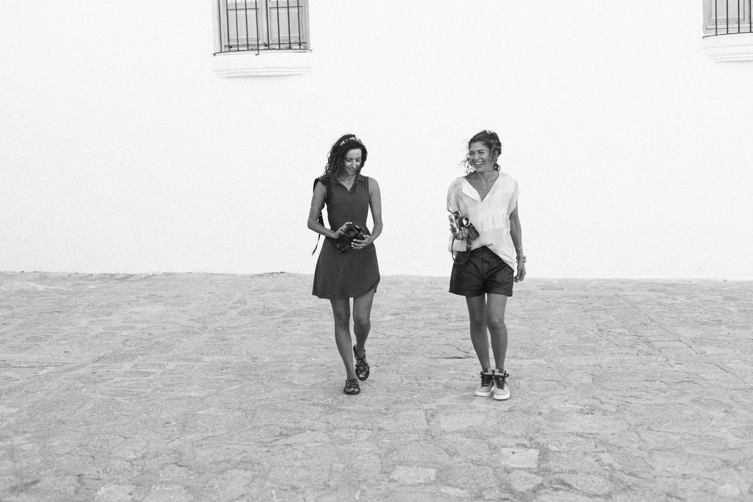 Two female photographers walk and laugh together 2