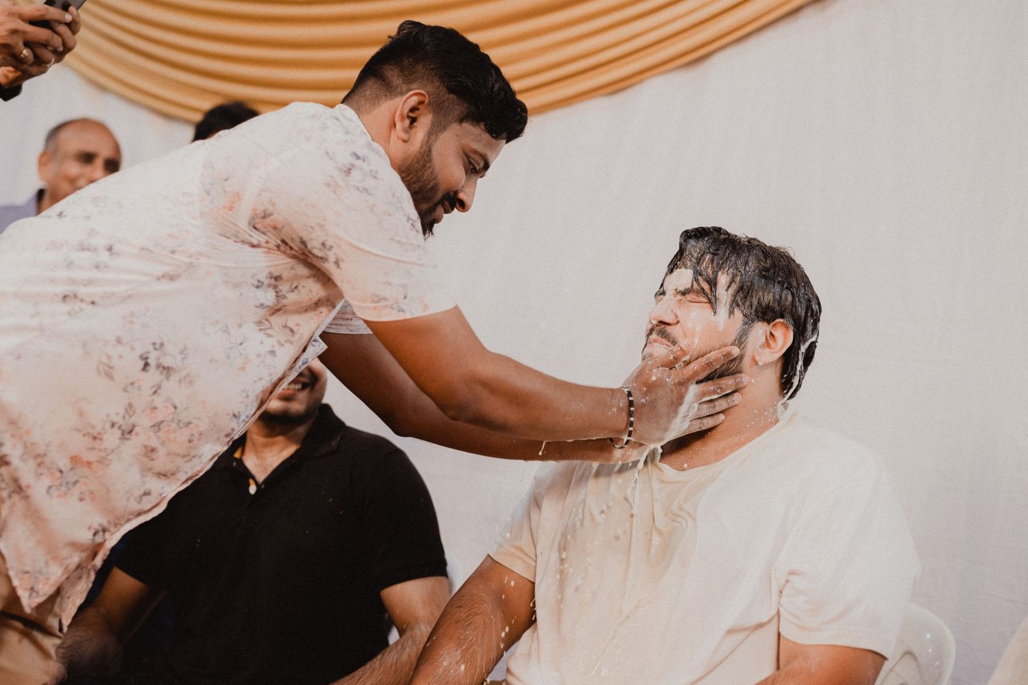 Guests interacting and celebrating at an indoor event with peach-colored draping.