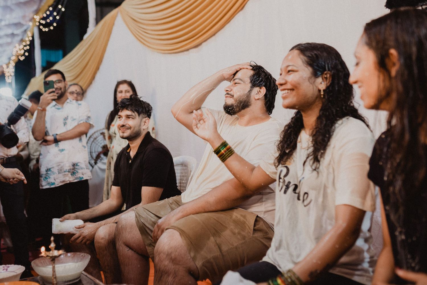 Celebratory gathering with people laughing under warm decorative draping.