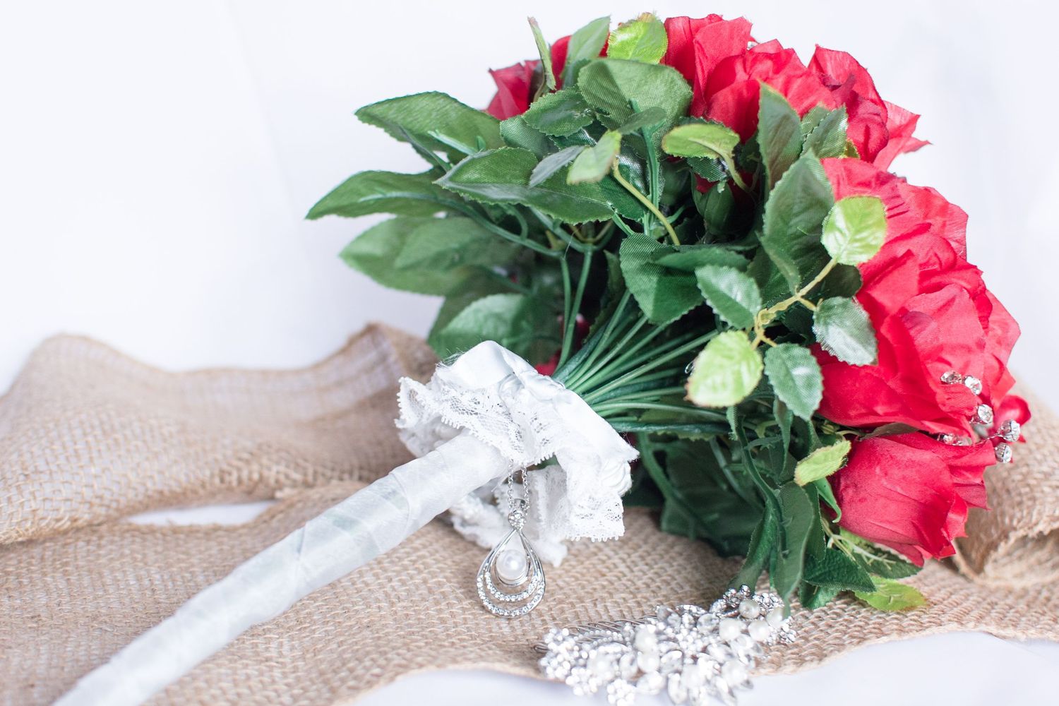 Red rose bridal bouquet wrapped in burlap with lace ribbon and pearls.