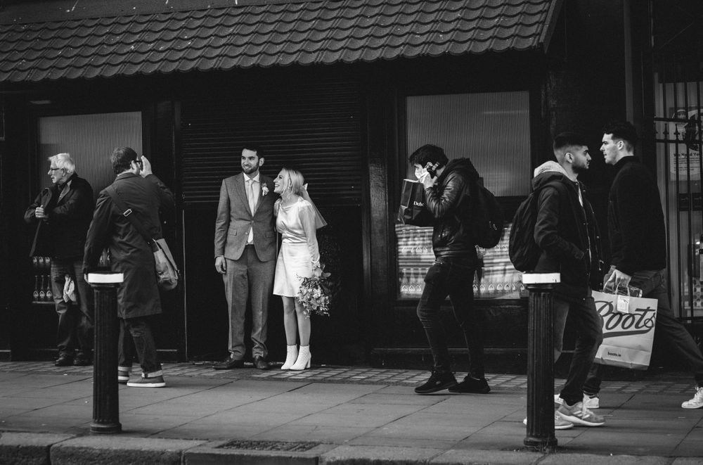 Vintage black and white street scene showing people waiting in line outside a storefront.