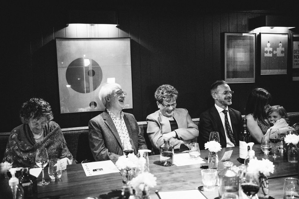 Wedding guests enjoying a celebratory dinner in black and white photography.