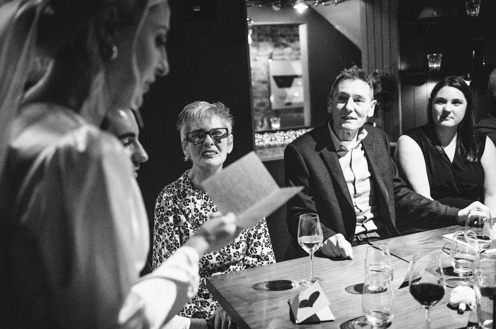 Black and white image of guests gathered around a table during a wedding reception.