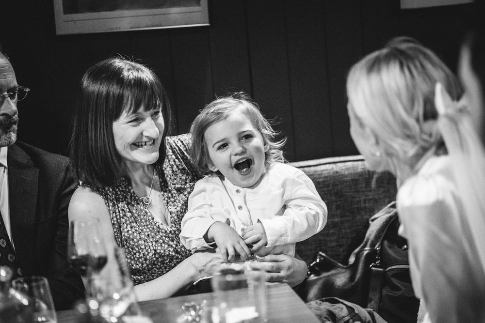 A joyful moment of laughter shared between guests during a celebration at a restaurant table.