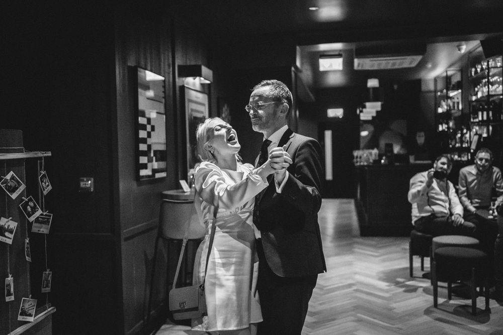 A black and white photograph of a couple dancing together in an indoor venue.