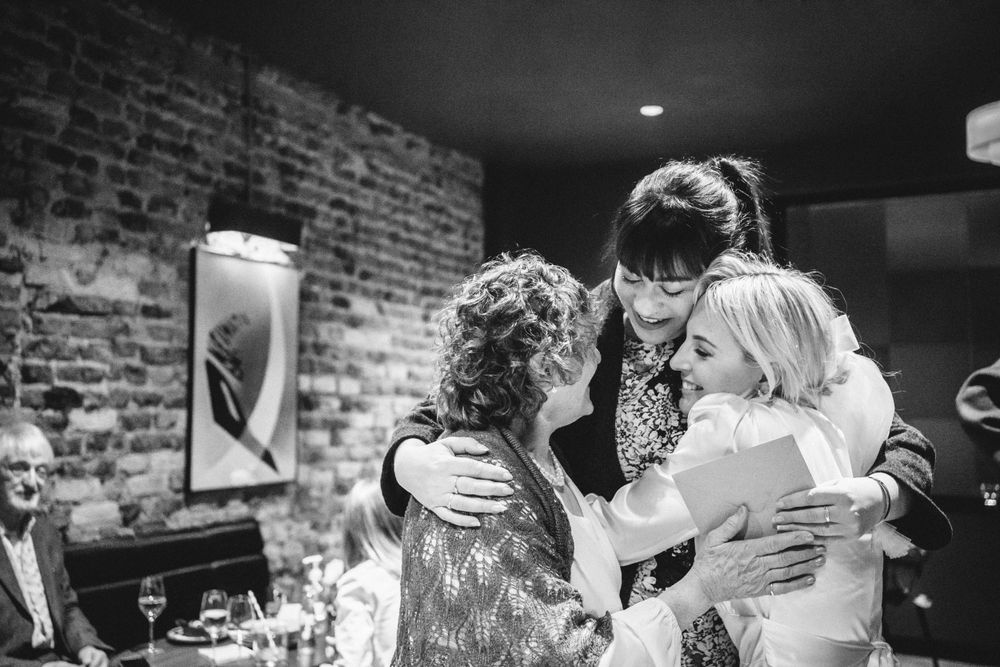 An emotional black and white photo of wedding guests embracing during the reception.
