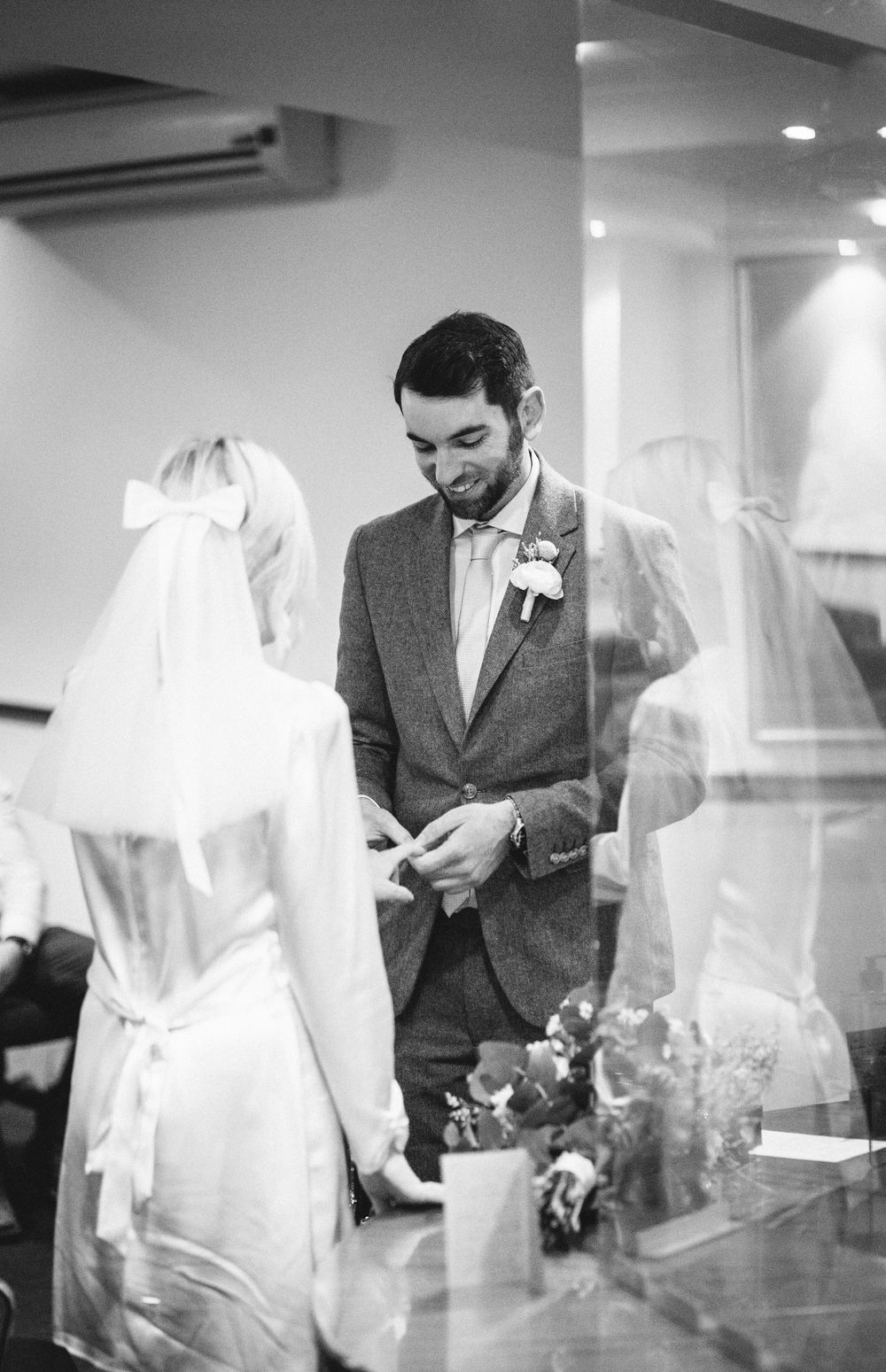 Black and white indoor ceremony capture showing exchange of rings.