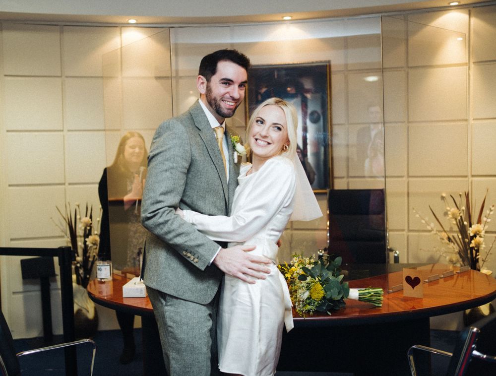 A couple embracing in a modern interior with decorative flowers and table settings.