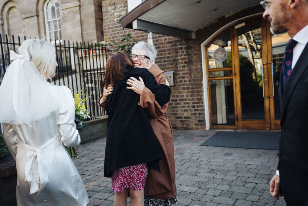 People hugging and celebrating outside a brick building entrance.