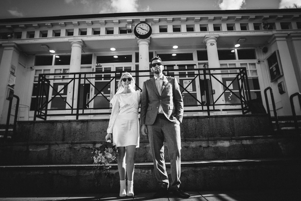 A couple poses on stone steps in front of a historic building in black and white.