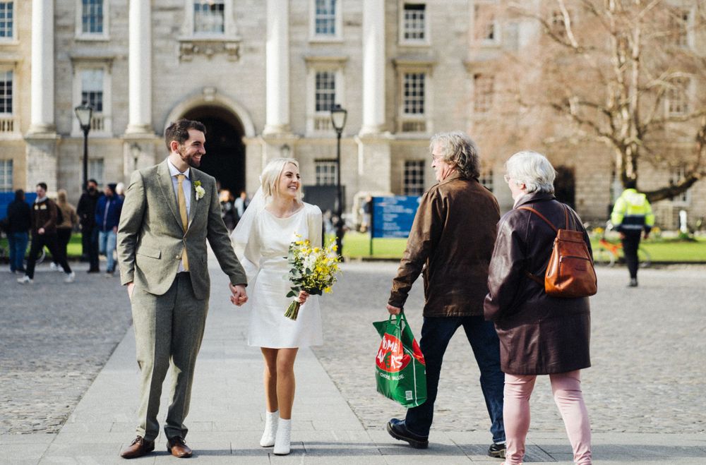 A couple walks through a historic courtyard as pedestrians pass by.