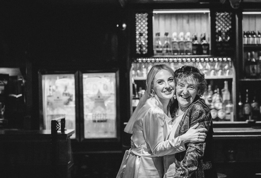 A black and white photo capturing a celebratory moment at a bar during a wedding reception.