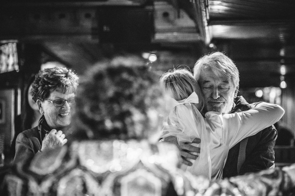 A black and white photo capturing movement and celebration at an indoor gathering.