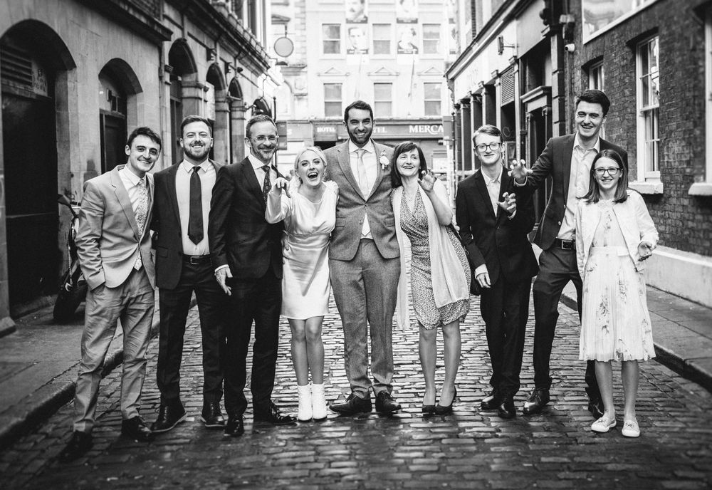A vintage-style black and white group photo on a cobblestone street.