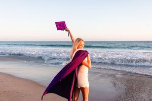 College grad session holding cap in the air in Dana Point