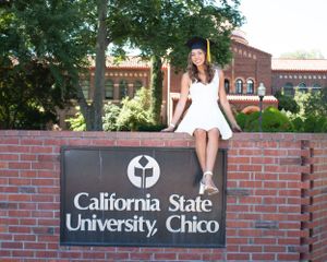 College grad posing with California State University, Chico sign
