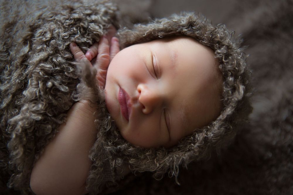 A sleeping baby wrapped in textured brown fabric.