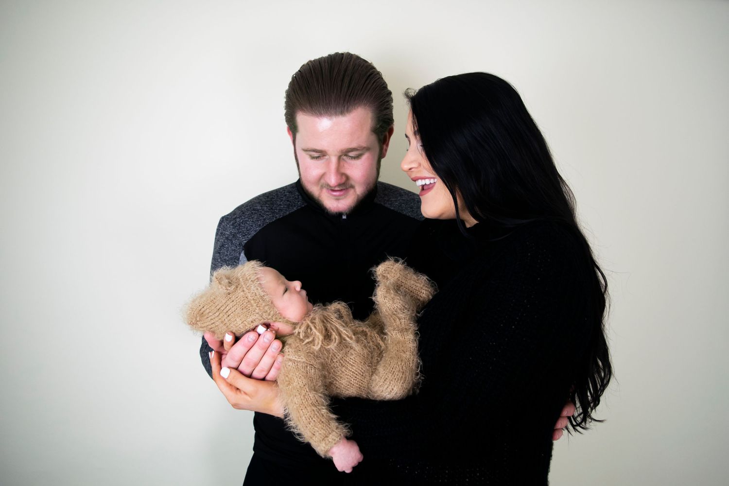family photograph with newborn and parents mum and dad holding baby in hands taken by heather katie photography.