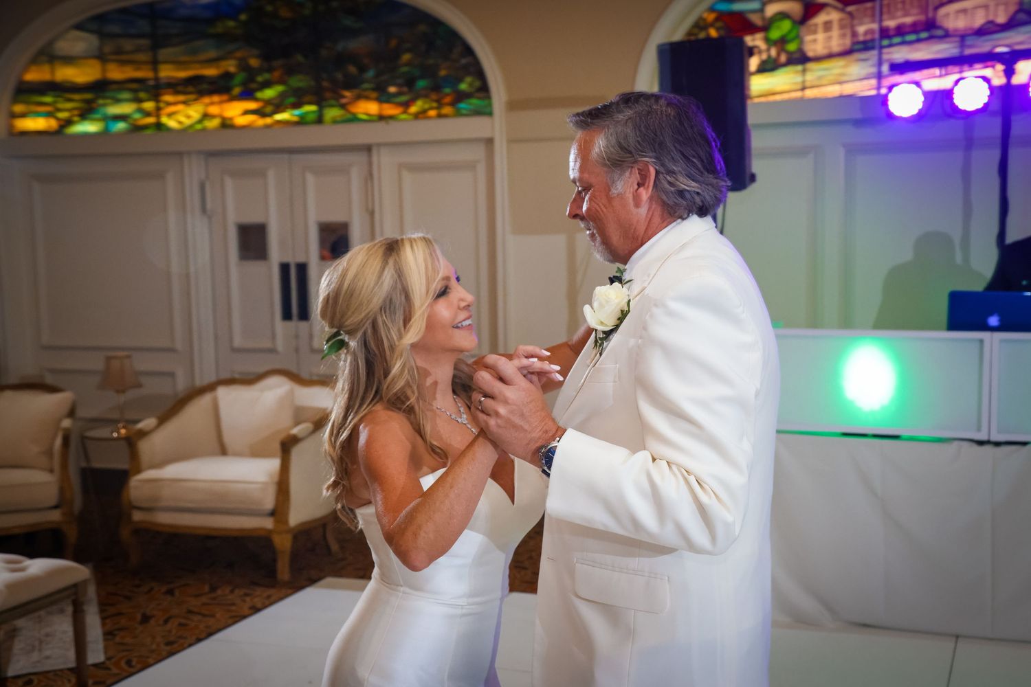 Romantic first dance moment under colorful venue lighting.