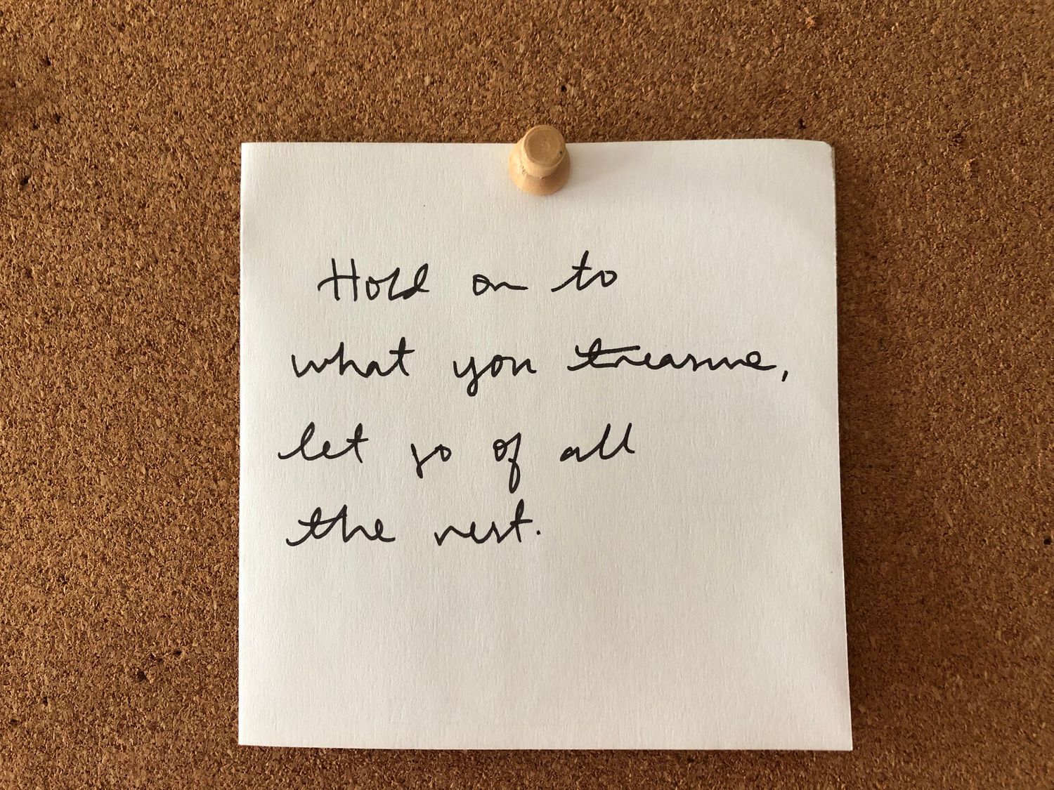 Handwritten note pinned to cork board with message about letting go.