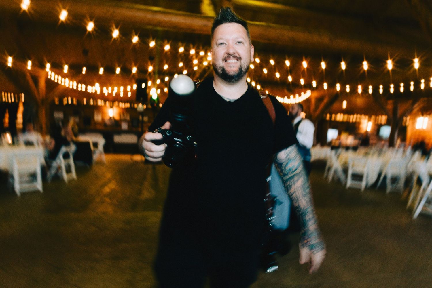 String lights illuminate an outdoor evening wedding reception area creating a warm ambiance.