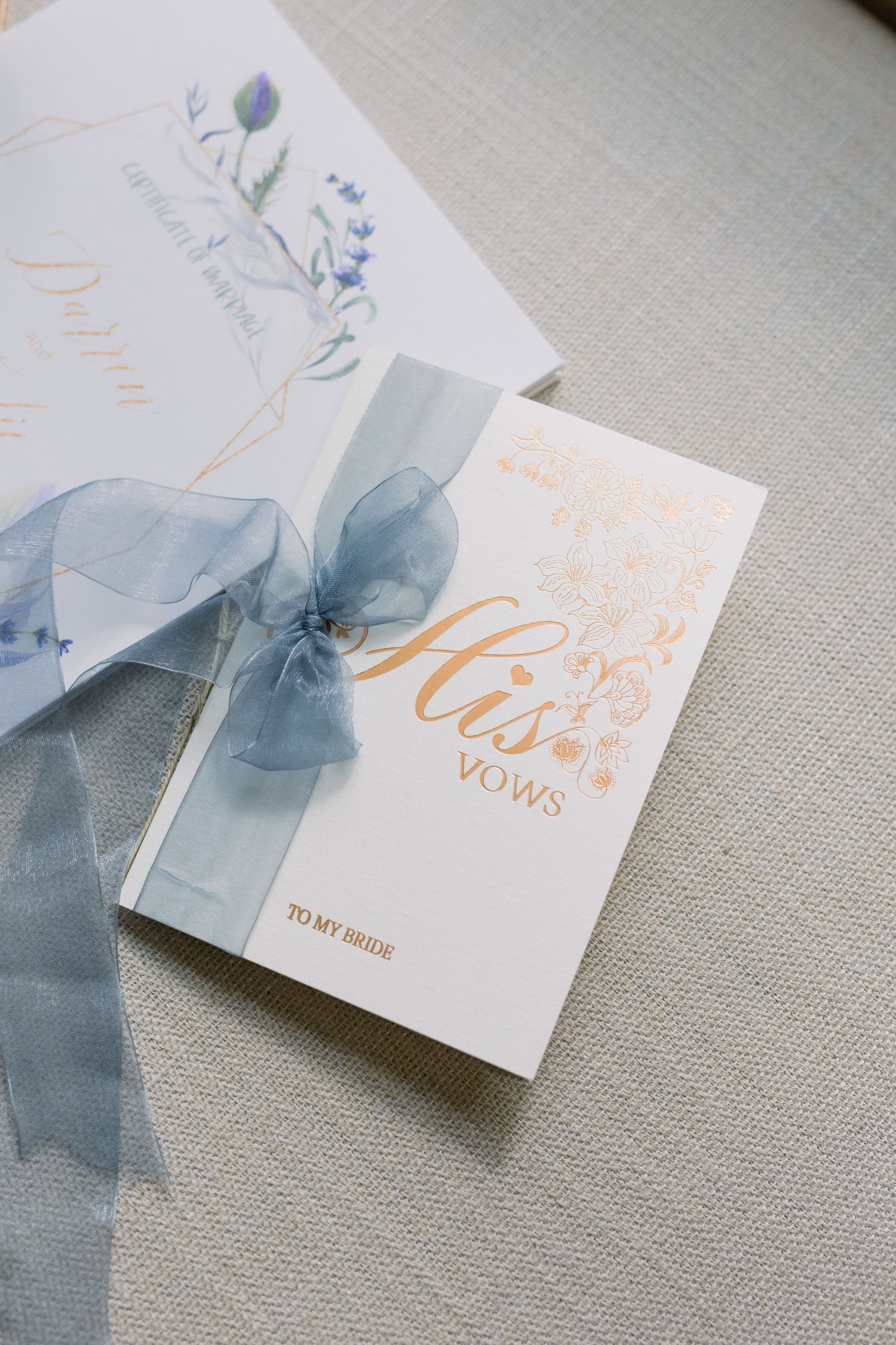 Wedding vow booklets with soft blue ribbons and elegant calligraphy.